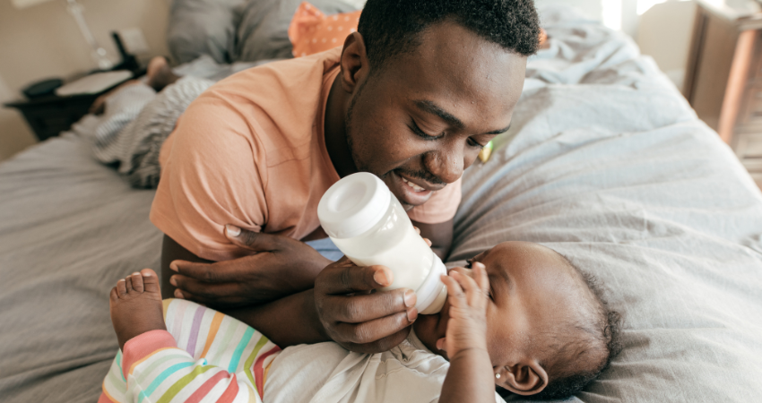 Black dad feeding baby with bottle